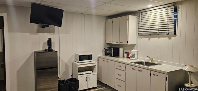 Kitchen featuring freestanding refrigerator, dark wood-type flooring, light countertops, white microwave, and white cabinets | Image 21
