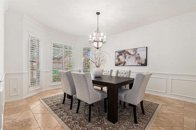 Holidays sharing a meal in this charming formal dining space, complete with patterned travertine tiled flooring, crown and box molding and a pretty chandelier will be the envy of all. | Image 4