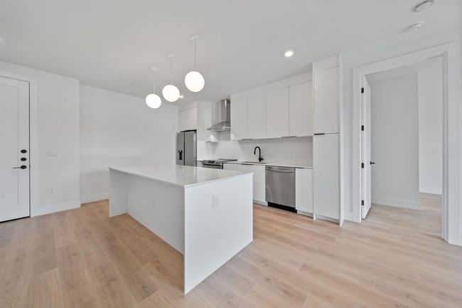 Carrara marble-style quartz countertops and modern white cabinetry finished off by matte black handles and hardware | Image 4