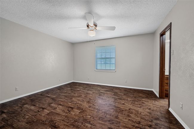 Spare room with baseboards, a textured ceiling, wood finished floors, and ceiling fan | Image 23
