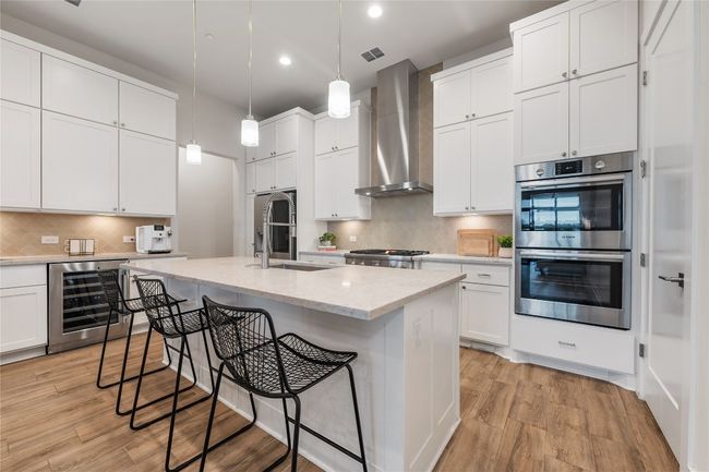 Elegant chef's kitchen with center island, Thermador gas stove, double oven, built in Jenn Air microwave, under cabinet lighting, wine fridge, and pantry. | Image 8