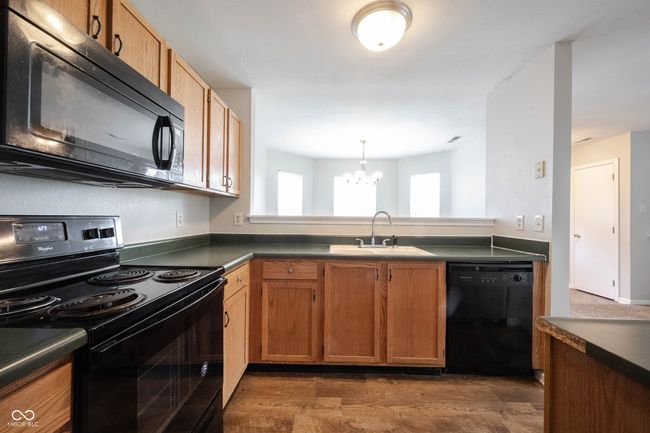 kitchen featuring a chandelier, dark countertops, a sink, and black appliances | Image 17