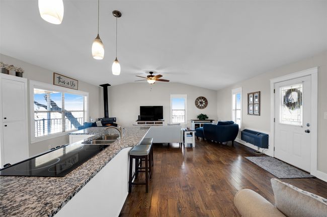Kitchen featuring a wood stove, open floor plan, black electric cooktop, ceiling fan, and vaulted ceiling | Image 6