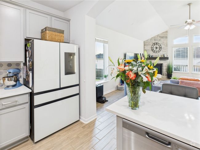 Kitchen with freestanding refrigerator, dishwasher, light countertops, lofted ceiling, and light wood-style flooring | Image 12