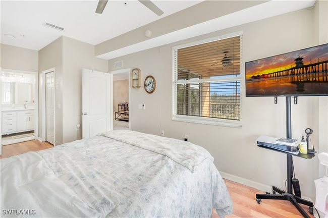 Bedroom with connected bathroom, light wood-type flooring, and ceiling fan | Image 13