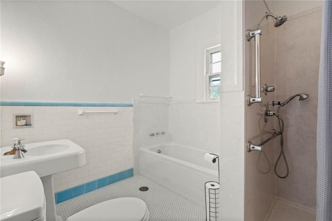 Hall Bathroom featuring tile walls, a shower and a tub, toilet, and tile flooring. | Image 21
