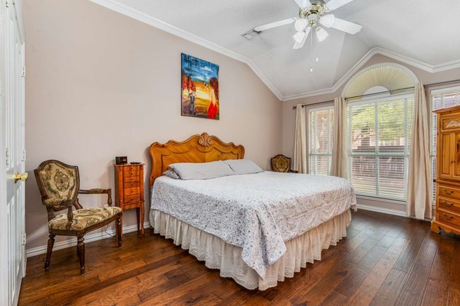 Bedroom with hardwood flooring, ornamental crown molding, vaulted ceiling, baseboards, and ceiling fan | Image 22