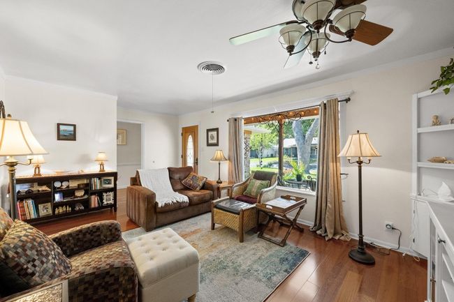 Living room featuring baseboards, crown molding, visible vents, ceiling fan, and wood finished floors | Image 5