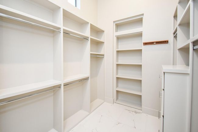 Secondary primary closet "for him" features secret room behind shelving. | Image 32