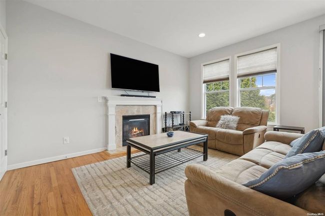 Living area featuring baseboards, light wood-type flooring, a glass covered fireplace, and recessed lighting | Image 7