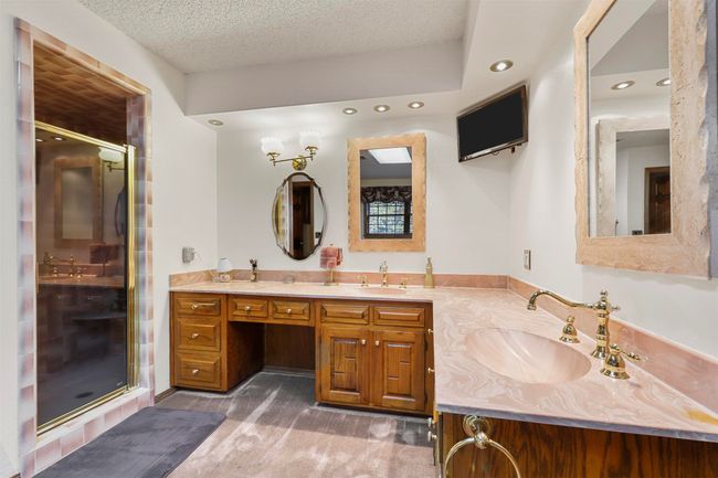 Bathroom with an enclosed shower, vanity, and a textured ceiling | Image 26