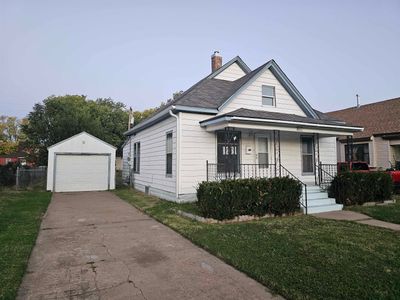 Bungalow featuring a front yard, a porch, a garage, and an outdoor structure | Image 1