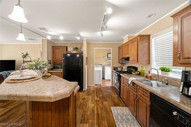 Kitchen with a textured ceiling, ornamental molding, black appliances, rail lighting, and sink | Image 9