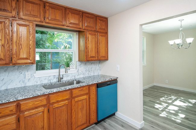 Kitchen with dishwashing machine, tasteful backsplash, and brown cabinetry | Image 10