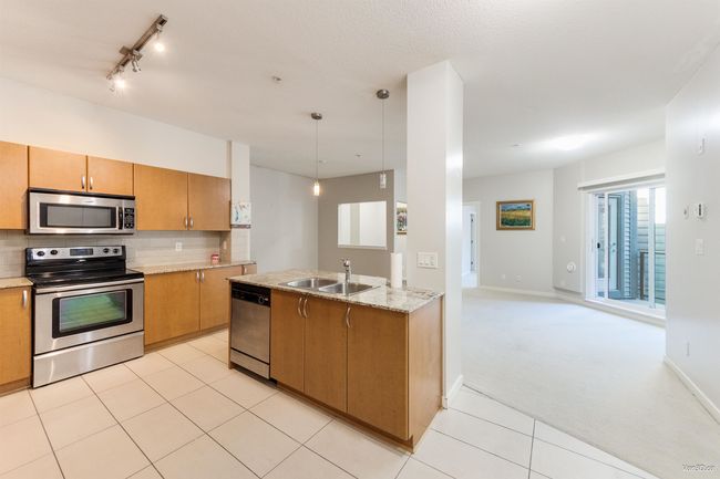 Kitchen with stainless steel appliances, light carpet, tasteful backsplash, pendant lighting, and open floor plan | Image 4