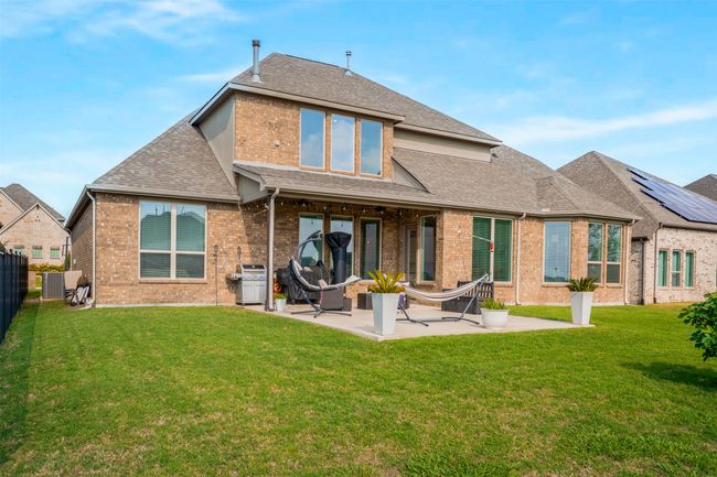 Rear view of house featuring a fenced backyard, a yard, brick siding, a patio, and roof with shingles | Image 35