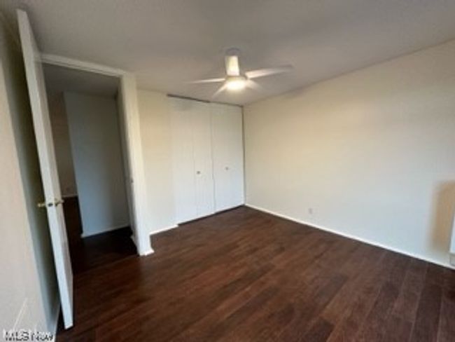 Unfurnished bedroom featuring ceiling fan, dark hardwood floors, and a closet | Image 17