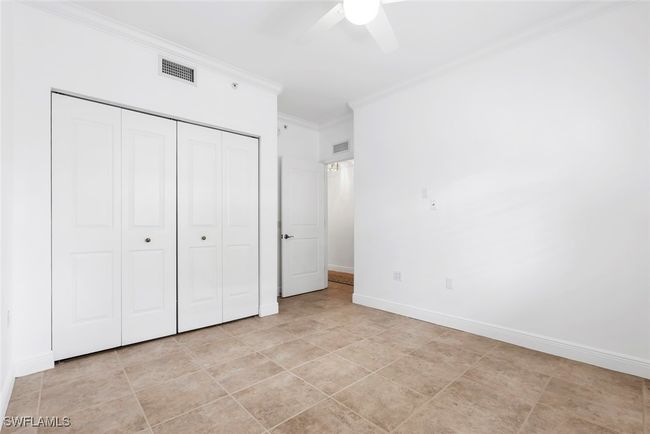 Unfurnished bedroom featuring a closet, ceiling fan, ornamental molding, and light tile patterned floors | Image 28
