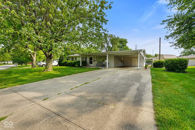 ranch-style house featuring concrete driveway, a front lawn, and a carport | Image 4