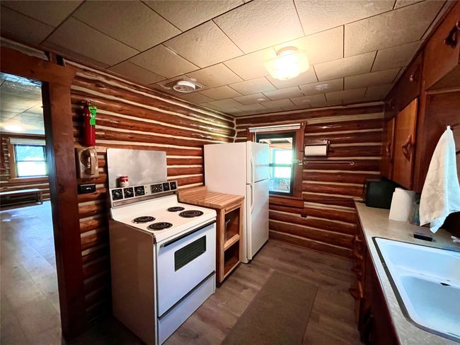 Kitchen with white appliances, rustic walls, dark wood-style flooring, and healthy amount of natural light | Image 17