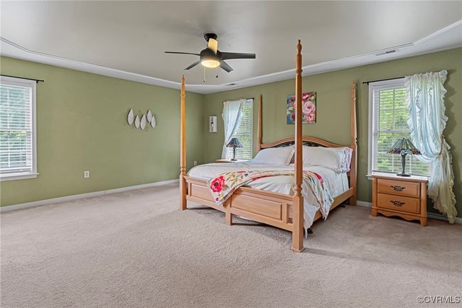 Bedroom featuring ceiling fan, baseboards, visible vents, and light carpet | Image 27