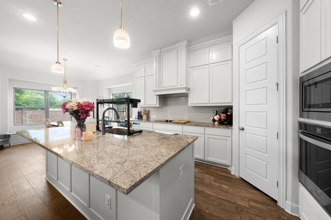Kitchen with appliances with stainless steel finishes, white cabinets, decorative backsplash, dark wood-type flooring, and recessed lighting | Image 9