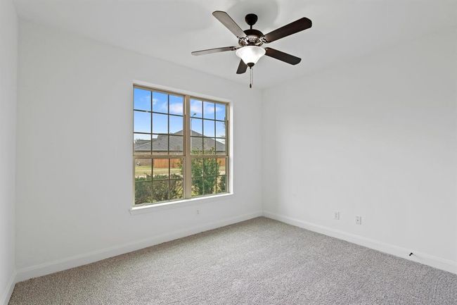 This spacious first-floor bedroom offers plush carpeting, a large window for natural light, and a sleek ceiling fan, creating a comfortable and inviting retreat! | Image 8