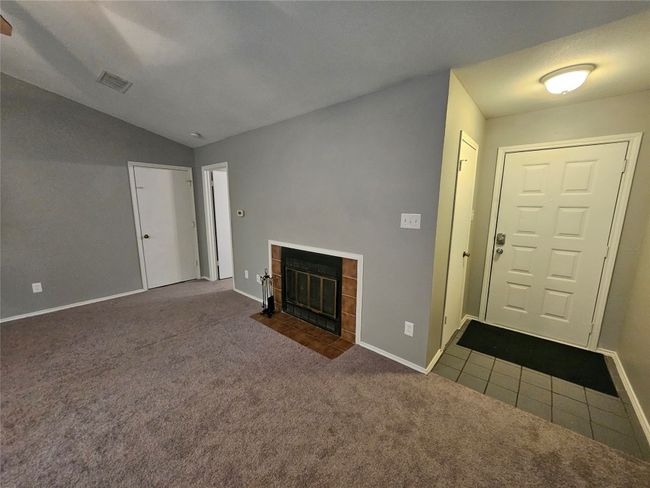 Unfurnished living room with carpet, a tiled fireplace, visible vents, and lofted ceiling | Image 9