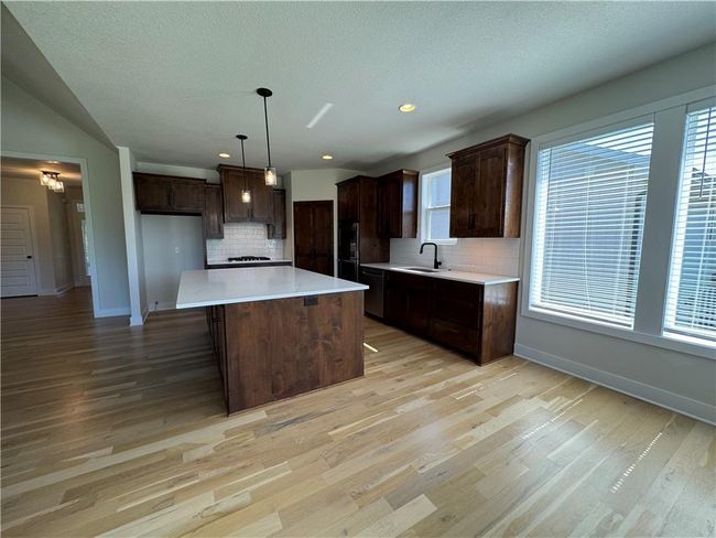 Kitchen with tasteful backsplash, dark brown cabinetry, plenty of natural light, light wood-type flooring, and recessed lighting | Image 19