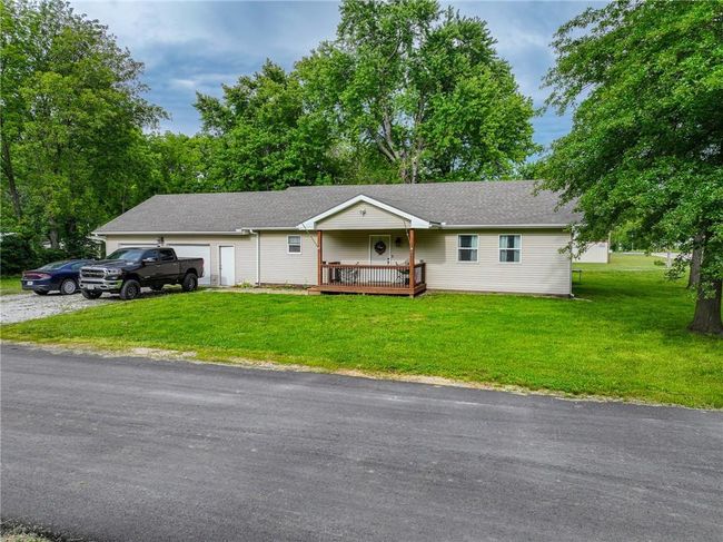 Ranch-style home with a front yard, an attached garage, a wooden deck, and roof with shingles | Image 7