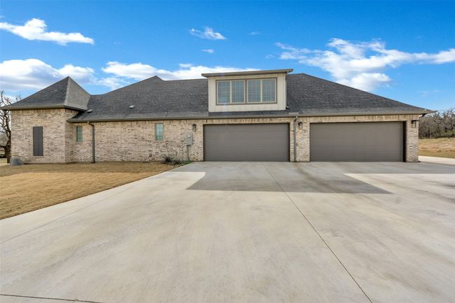 View of front of house with brick siding, roof with shingles, concrete driveway, and a front yard | Image 38