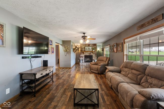 living room featuring baseboards, a fireplace, dark wood-style floors, a textured ceiling, and ceiling fan | Image 12