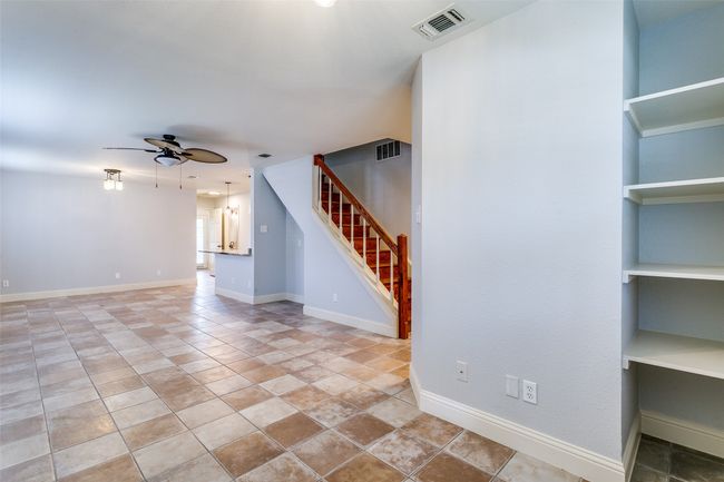 Unfurnished living room with a ceiling fan and stairs | Image 6