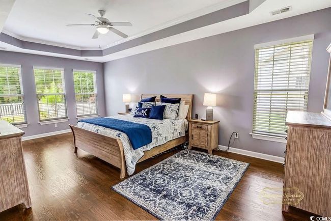 Bedroom with a raised ceiling, dark wood finished floors, crown molding, and ceiling fan | Image 17