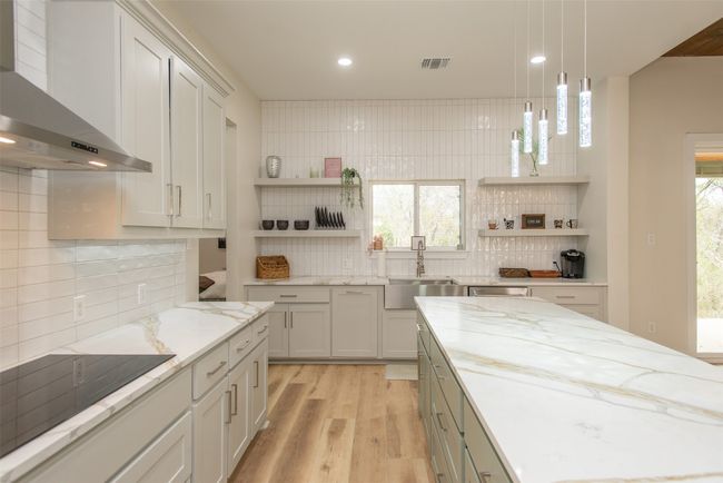 Kitchen with wall chimney range hood, sink, decorative backsplash, light wood-type flooring, and black electric cooktop | Image 8