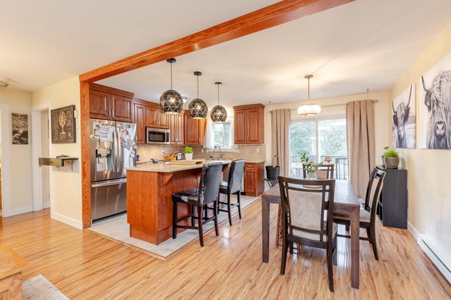 Dining area featuring light wood finished floors, a baseboard heating unit, and beamed ceiling | Image 7
