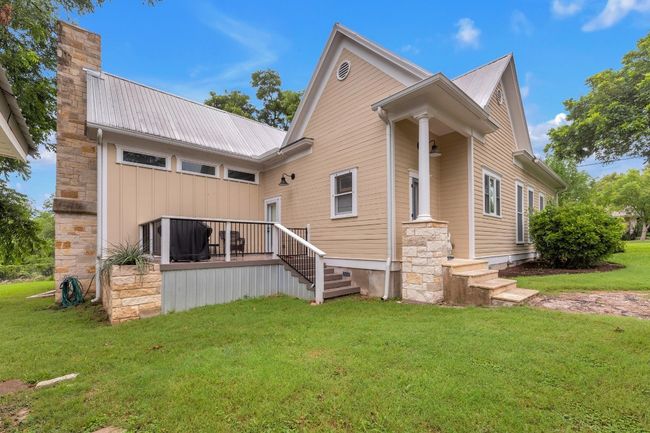 Back of property with a lawn, a metal roof, a chimney, and board and batten siding | Image 38