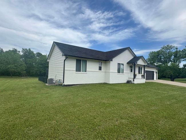 View of front of house featuring a garage, cooling unit, driveway, a front yard, and brick siding | Image 4
