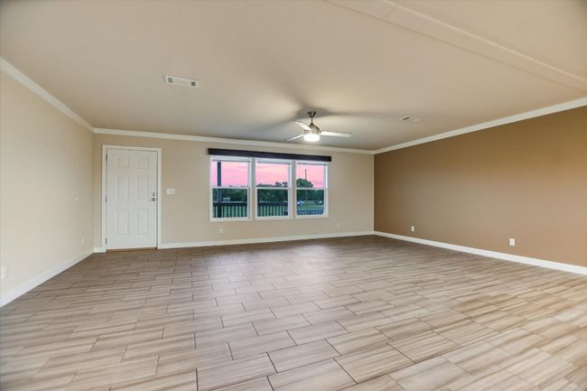 Spare room with crown molding, ceiling fan, and baseboards | Image 8