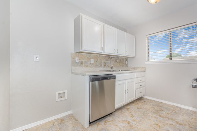 Kitchen featuring stainless steel dishwasher, light countertops, tasteful backsplash, and white cabinetry | Image 8