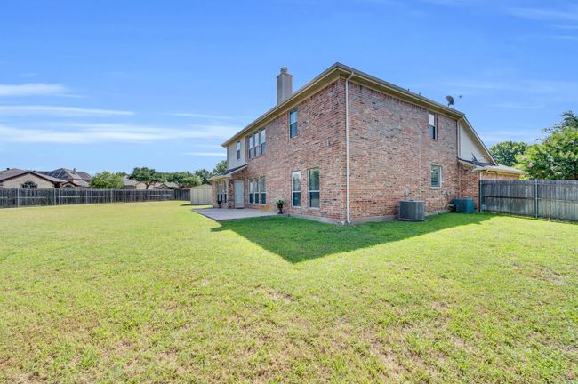 Rear view of property with brick siding, a chimney, a patio area, and a fenced backyard | Image 34