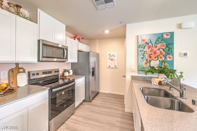 Kitchen with recessed lighting, appliances with stainless steel finishes, white cabinets, a sink, and light wood-type flooring | Image 14