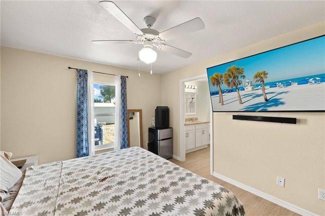 Bedroom with baseboards, light wood finished floors, freestanding refrigerator, a ceiling fan, and ensuite bathroom | Image 13