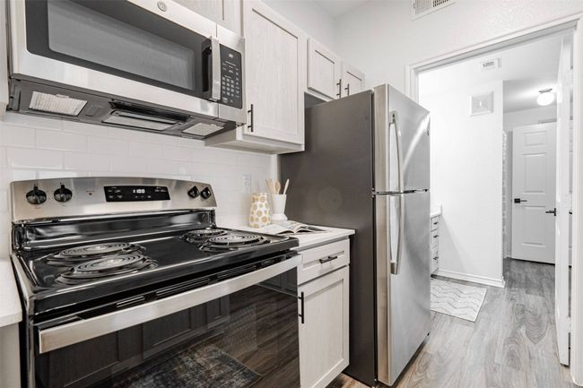 Kitchen featuring white cabinets, backsplash, light wood-type flooring, and stainless steel appliances | Image 31