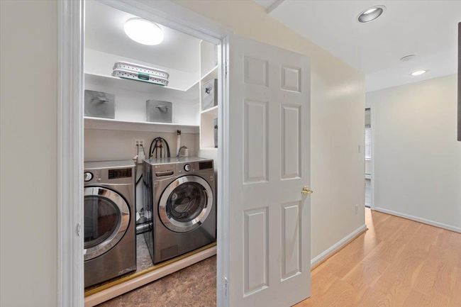 Laundry area with washing machine and clothes dryer, baseboards, wood finished floors. | Image 13