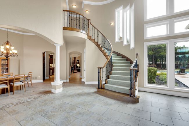 Foyer featuring arched walkways, a towering ceiling, a chandelier, decorative columns, and stairway | Image 10