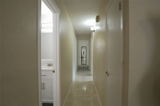 Hall featuring a textured ceiling, baseboards, a textured wall, a sink, and light tile patterned flooring | Image 18
