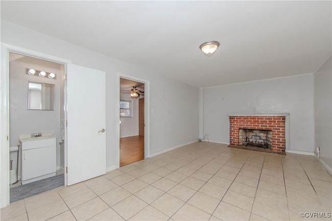 Unfurnished living room featuring ceiling fan, light tile patterned flooring, and a brick fireplace | Image 11