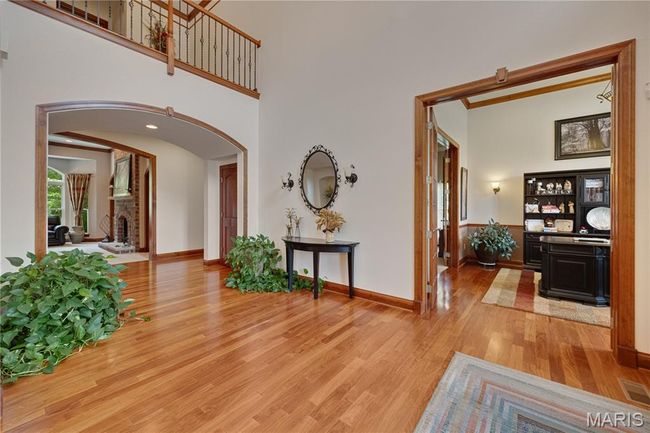 Entryway featuring arched walkways, light wood-type flooring, a brick fireplace, and a high ceiling | Image 43