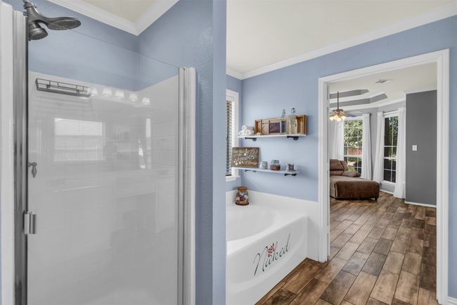 Bathroom featuring crown molding, ceiling fan, wood-type flooring, and plus walk in shower | Image 11